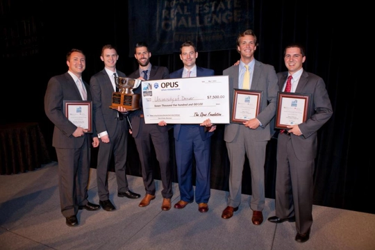 group of men standing with large check, plaques and trophy